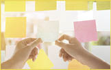 Creative business people reading sticky notes on glass wall with colleague working use post it notes to share idea discussing and teamwork, brainstorming concept.Closeup shot.