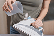 Woman load water in iron. Prepare iron for ironing