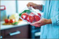 Woman packaged fresh vegetables using food film for food storage in fridge