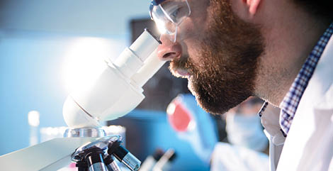 Scientist in laboratory environment using a microscope